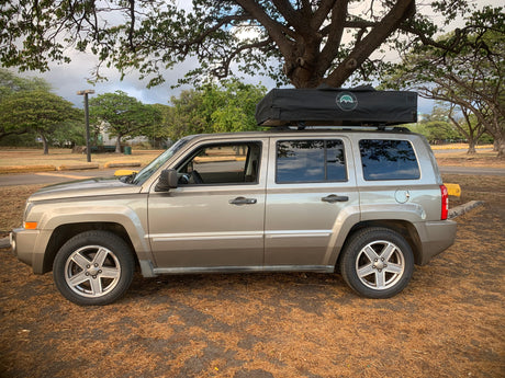 A gold Jeep Patriot SUV with a rooftop tent, ideal for RV rental trips and overland camping adventures.