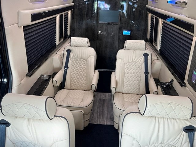 Luxurious RV rental interior: cream leather captain's chairs & dark wood accents. Ideal for comfortable travel.