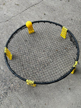 Spikeball set with black net, yellow ball and feet on concrete. Great for outdoor fun on your RV rental trip!