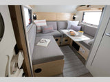 Cozy rv rental interior: a U-shaped dinette with gray cushions, table, book, and rug. Ideal for compact travel.