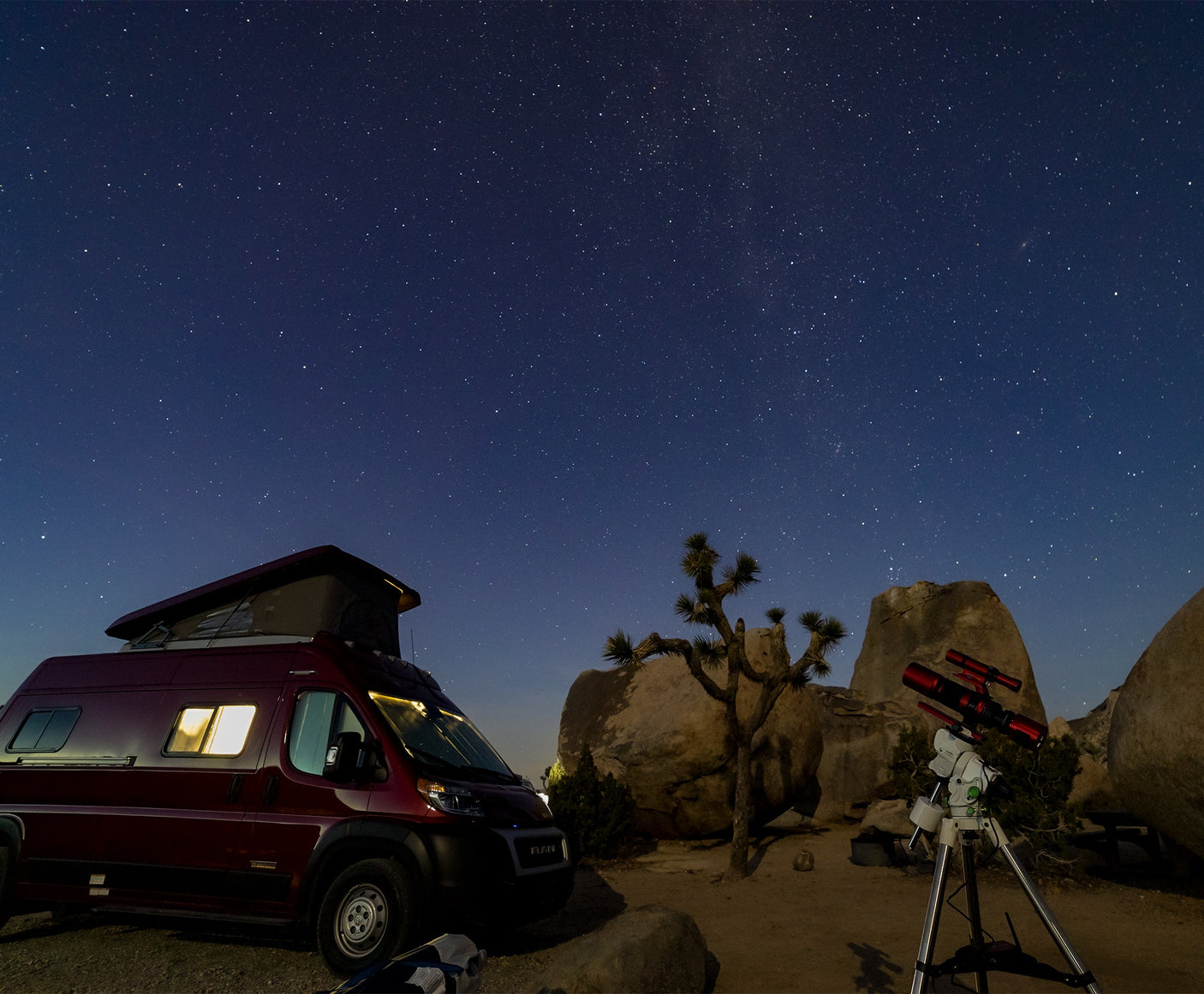 Stargazing in the desert with an RV rental. A pop-top RV and telescope are set among Joshua trees under a starry sky.
