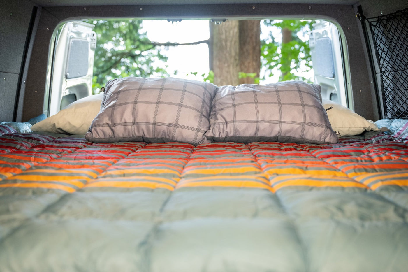 Cozy RV rental bed with open back doors revealing a natural view. Perfect for van life adventures from inside a campervan. — photo 17