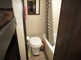 Compact RV rental bathroom features a toilet, shower/tub with curtain, and mirror. Practical and efficient interior for travel.