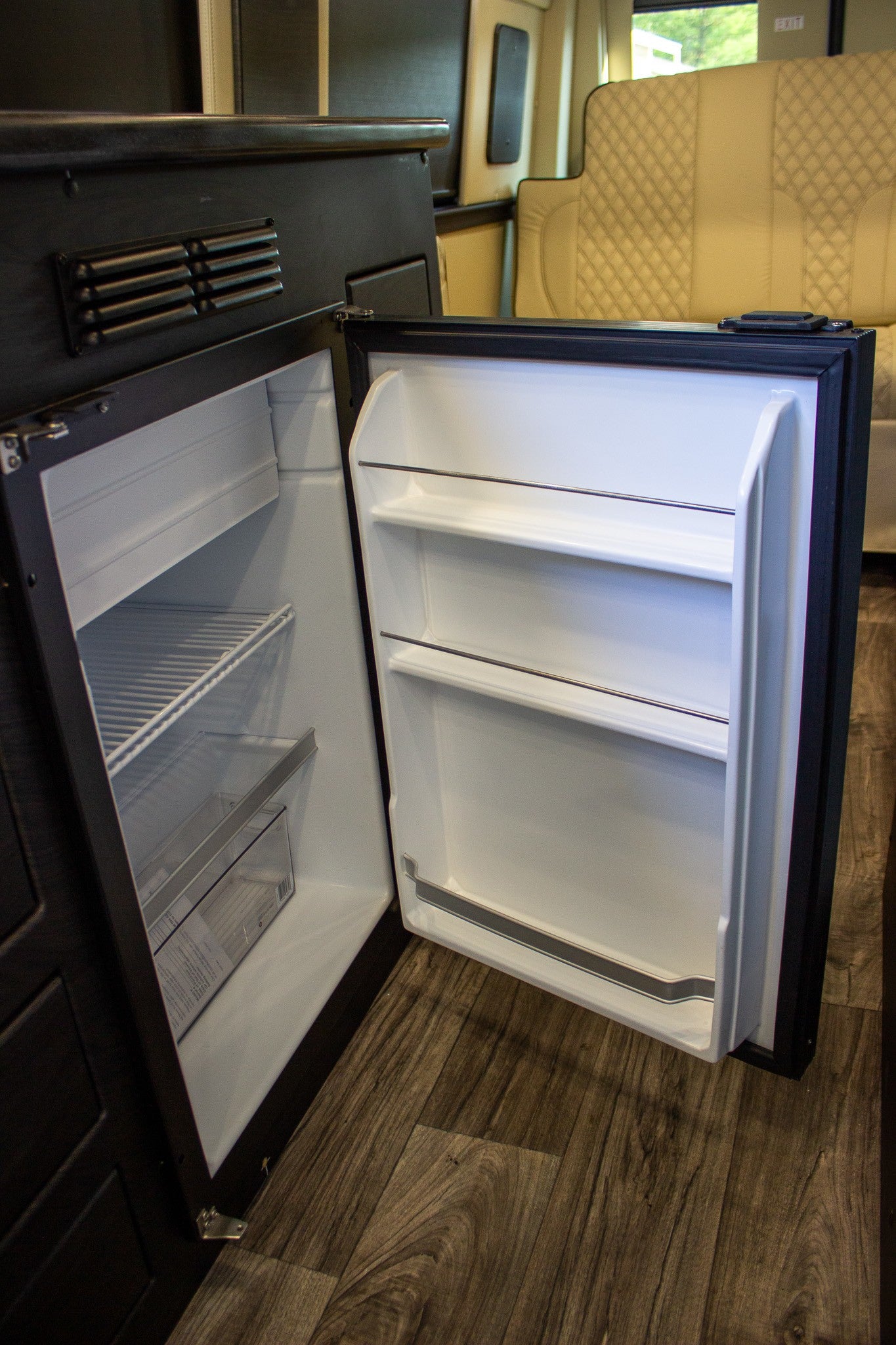 RV rental: Inside a modern RV, a clean, open mini-refrigerator and freezer await your travel essentials.