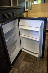 RV rental: Inside a modern RV, a clean, open mini-refrigerator and freezer await your travel essentials.