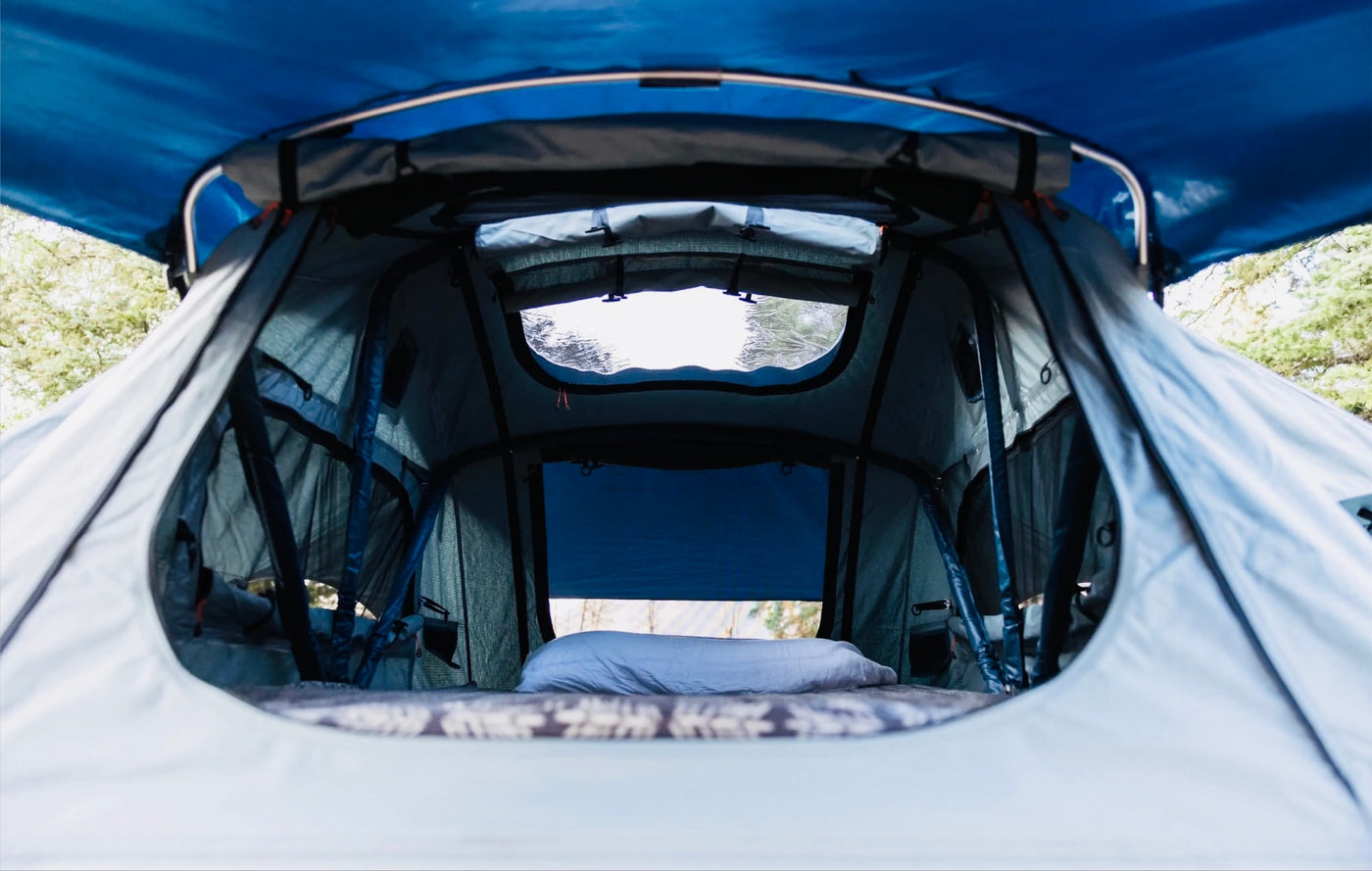 Cozy rooftop tent interior, featuring a mattress and pillow. Perfect for your RV rental camping adventure, with windows and a blue canopy. — photo 17