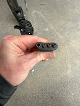 A hand holds a black 4-pin trailer connector (one large, three small holes), vital for RV rental lighting. Hitch in background.