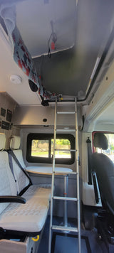 RV rental interior: Features a practical ladder to a bunk bed, cushioned seating area, and a table setup for comfortable travel.