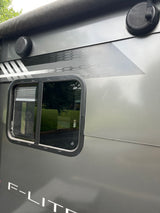 This RV rental's gray exterior features a window, dual outdoor speakers, and decorative honeycomb and stripe decals.