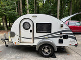 A white T@G teardrop camper, ideal for an rv rental or camping trip, is parked outdoors near trees.