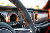 Experience comfort in our RV rental fleet. Detailed interior view showing a leather steering wheel with orange stitching and dashboard controls.