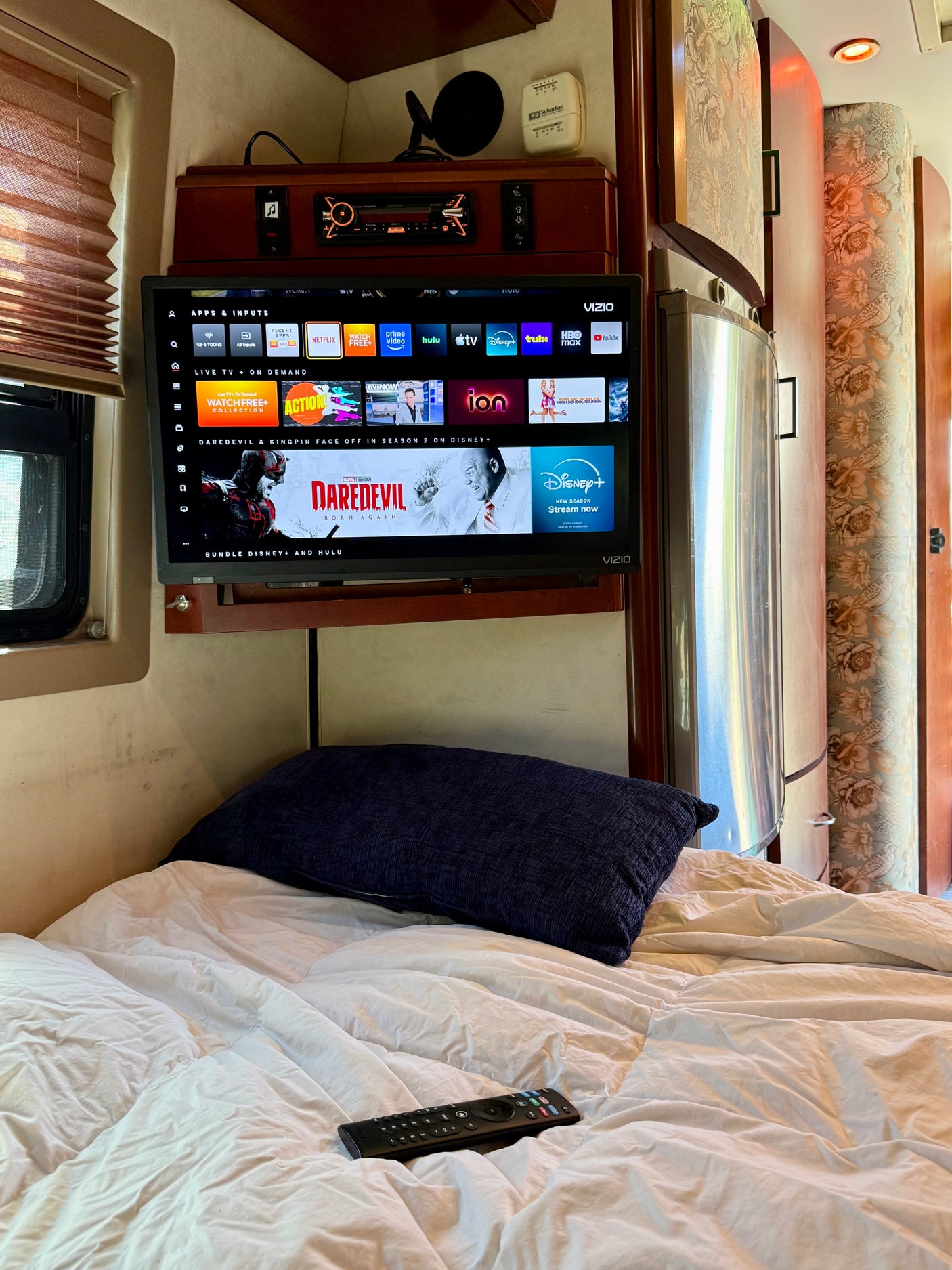 RV rental interior featuring a cozy bedroom, Vizio smart TV displaying streaming apps like Daredevil, and entertainment console.