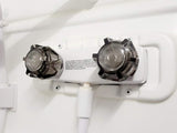 This RV rental's white shower faucet features dual clear handles and a hose connection. Note visible text on backflow prevention.