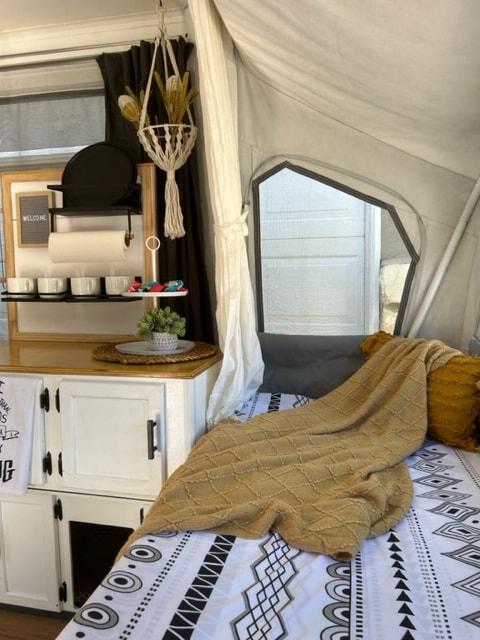Cozy RV rental interior showcasing a bed, textured blanket, and decorated storage space. Perfect for your next adventure. — photo 15