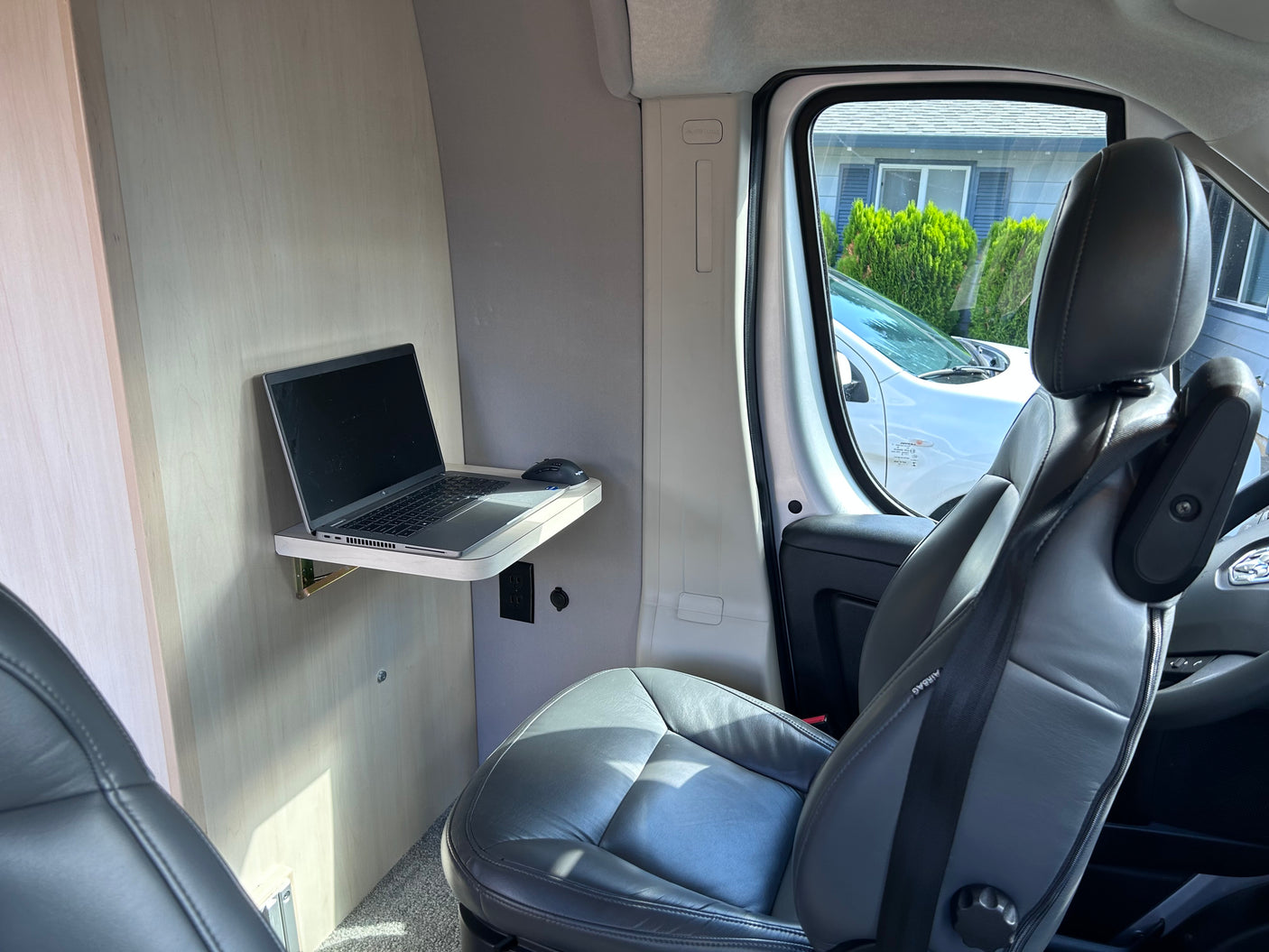 Mobile office setup in an RV rental: laptop on a fold-down desk, with power outlets and plush seating.