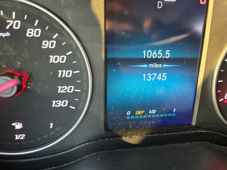 RV rental dashboard: 13,745 total miles, 1065.5 trip miles, 1/2 fuel, and near-full Diesel Exhaust Fluid (DEF) level.