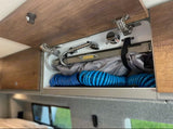 Compact RV rental shower system with coiled hoses and controls neatly stored in an overhead cabinet for easy access.