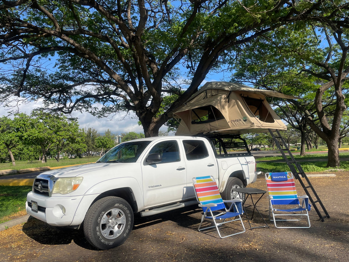 White Tacoma truck with rooftop tent & chairs, offering a unique RV rental camping experience under trees. — photo 11