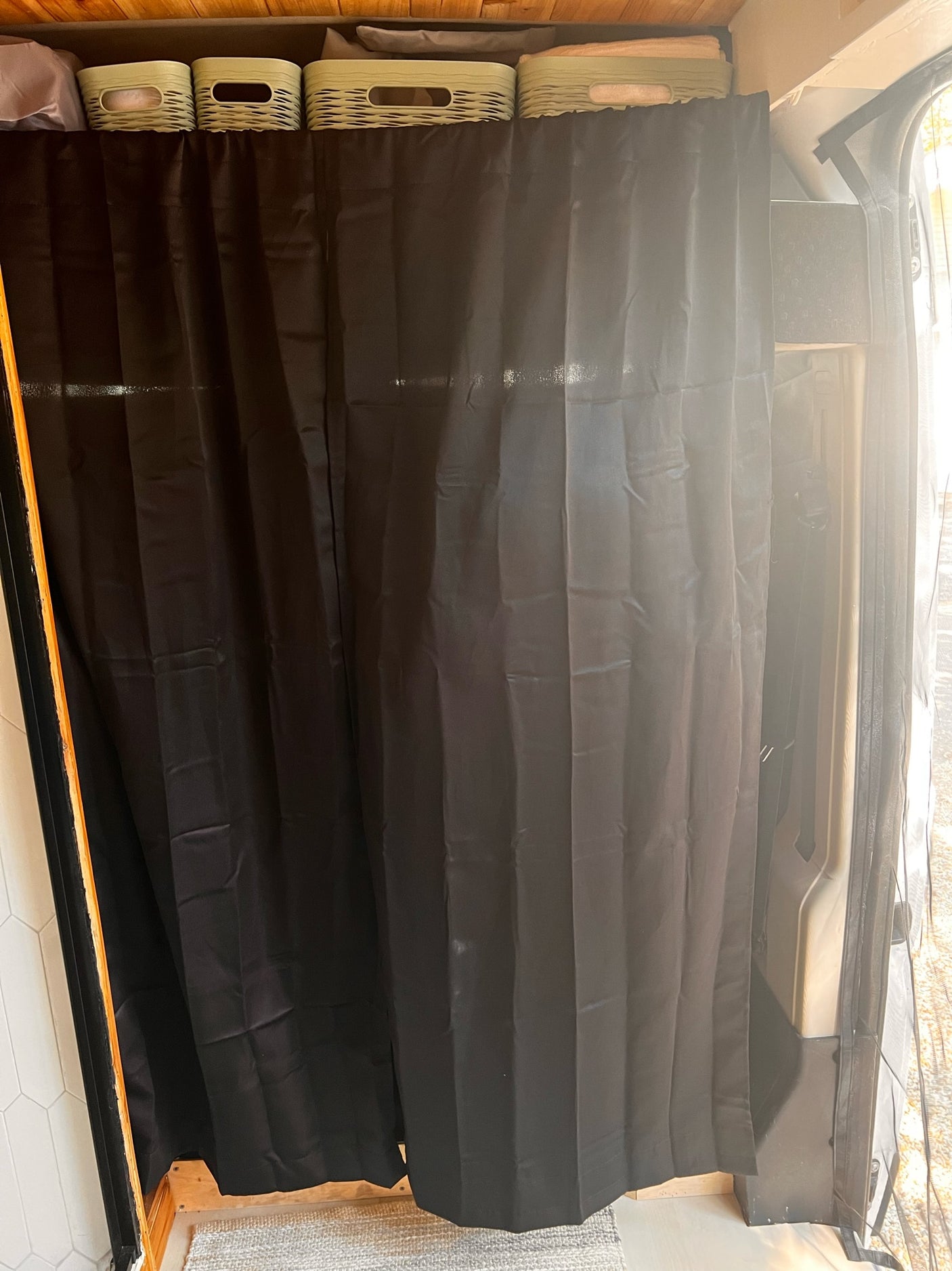 RV rental interior: Black privacy curtain and overhead storage baskets for organized, compact living.
