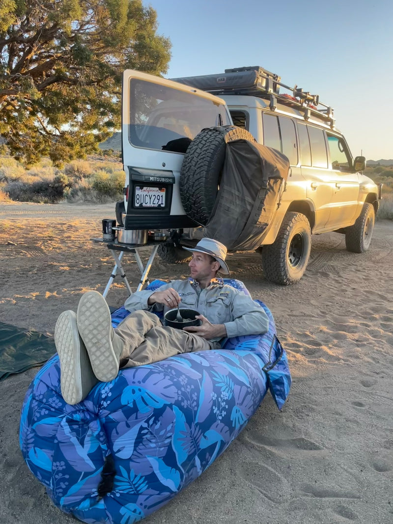 Man enjoys a meal from an inflatable chair next to his overlanding SUV. An ideal RV rental for desert camping adventures. — photo 15