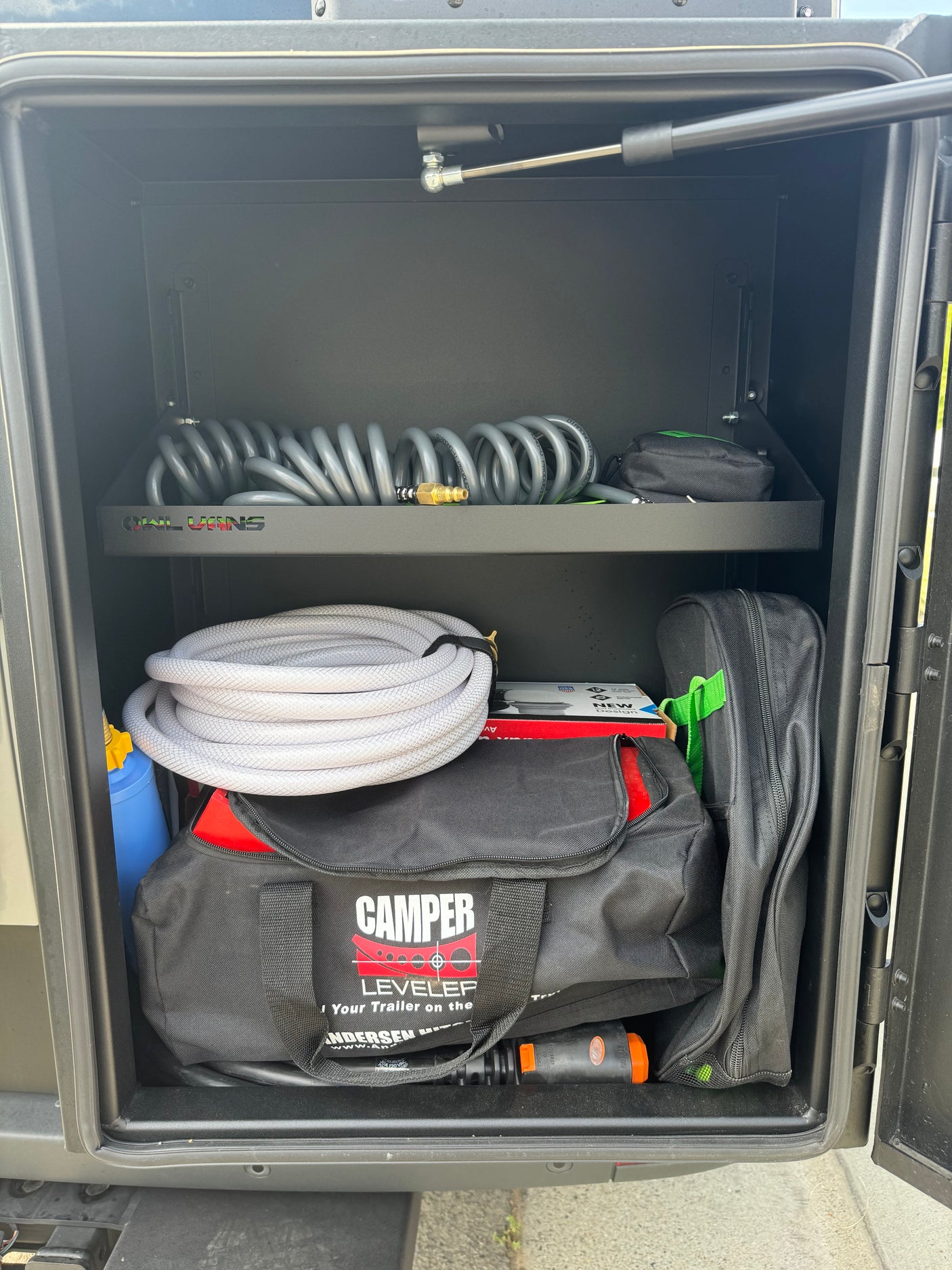Organized RV rental storage showing hoses, leveling blocks (Camper Leveler), and essential camping gear. Ready for adventure!