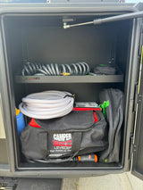 Organized RV rental storage showing hoses, leveling blocks (Camper Leveler), and essential camping gear. Ready for adventure!