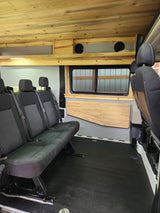 Spacious RV rental interior featuring custom wood paneling, comfortable seating, and a large window. Adventure awaits!