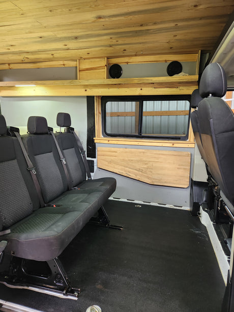 Spacious RV rental interior featuring custom wood paneling, comfortable seating, and a large window. Adventure awaits!