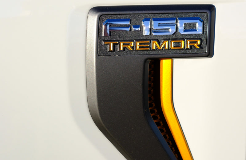 Chrome F-150 & gold TREMOR badge on white truck, with orange trim, ready for rv rental towing. — photo 14