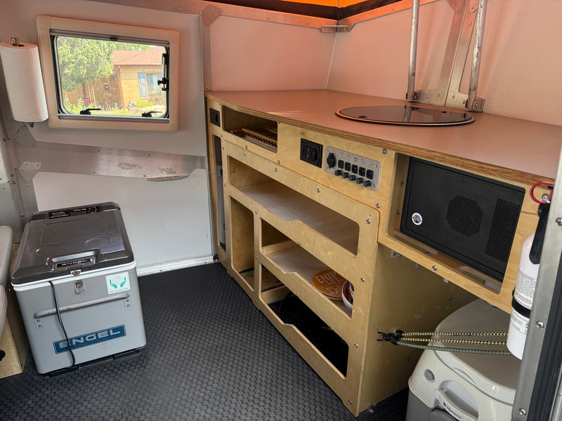 Compact RV rental interior featuring a kitchenette, Engel fridge, power panel, and Dometic toilet for convenience. — photo 5