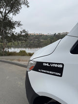 A white OWL VANS Ultimate Edition camper van parked by a scenic lake; an ideal rv rental for travel.