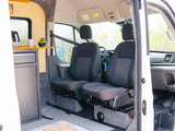 Interior of an RV rental camper van, showing kitchen area, front seats, and a custom build with amenities.
