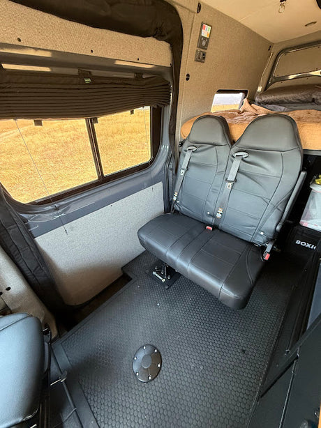RV rental van interior: black rear seats, window with blind, and a bed visible. Perfect for road trips.