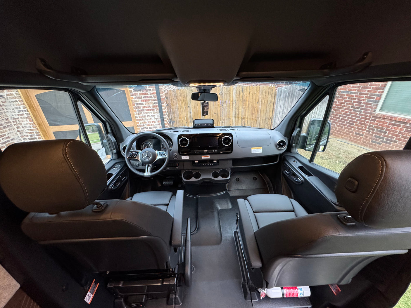 RV rental interior: wide view of the modern cockpit, dashboard, steering wheel, and both front seats of a campervan.