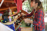 A woman in a plaid shirt cooks in a tidy RV kitchen. Perfect for your next RV rental camping trip.