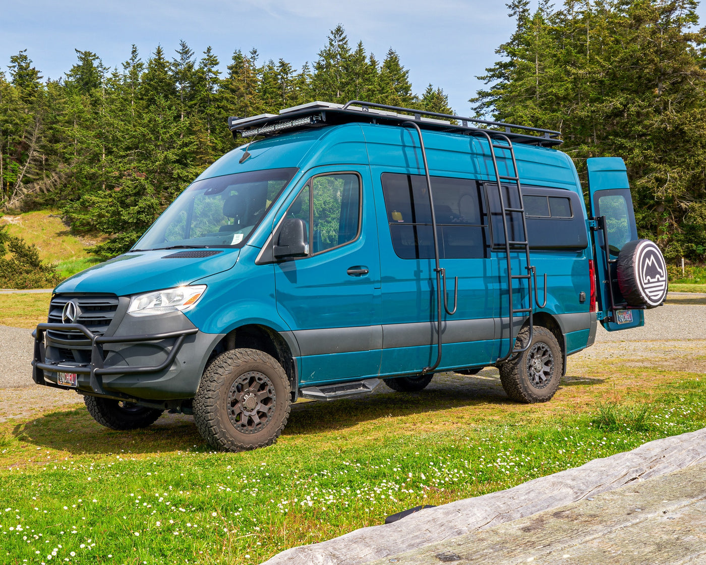 This teal, rugged Mercedes Sprinter adventure van, equipped for off-road travel, is a top choice for an RV rental, parked by a forest. — photo 15