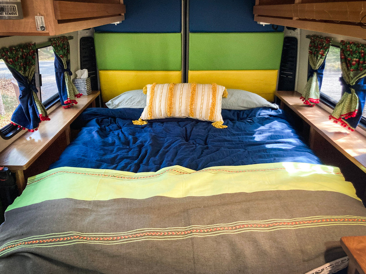 Cozy RV rental bedroom with colorful headboard, blue bedding, and berry-patterned curtains. Perfect for travel. — photo 3