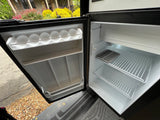 Empty compact fridge in an RV rental, showing clean interior with shelves and an egg tray. Ideal for trips.