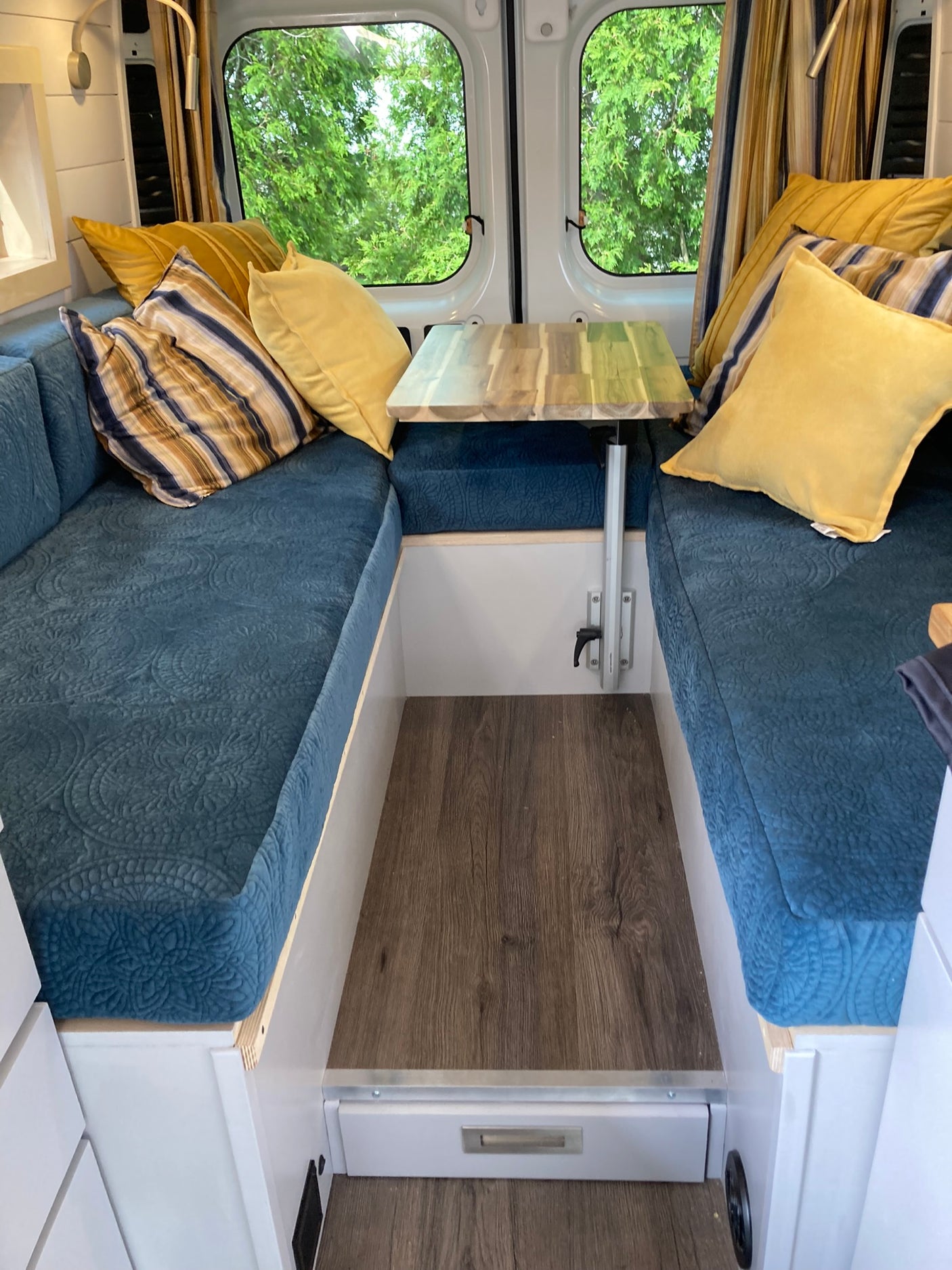 Cozy RV rental dinette with comfortable blue seating, bright pillows, and a compact wooden table, ready for travel adventures.