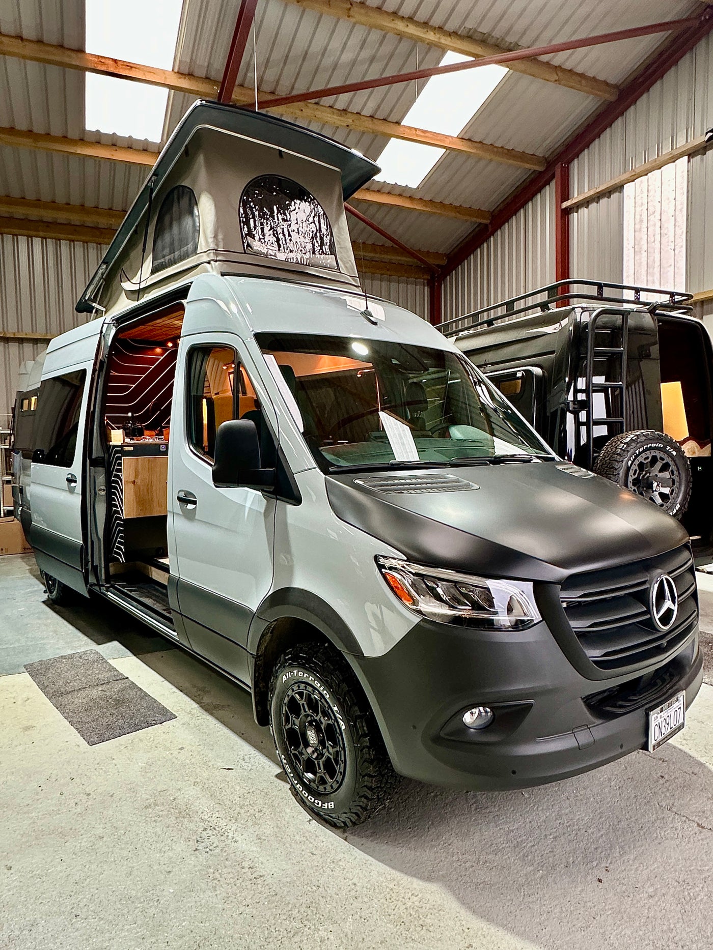 This custom Mercedes-Benz Sprinter camper van, ideal for RV rental, features a pop-top and stylish interior. — photo 12