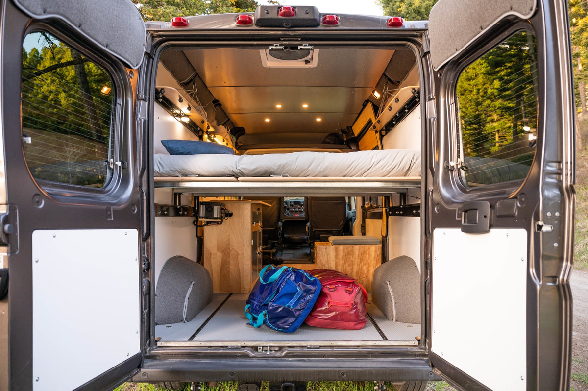 Spacious camper van interior, perfect for your next RV rental adventure. Features a comfy bed, ample storage, and warm lighting. — photo 4