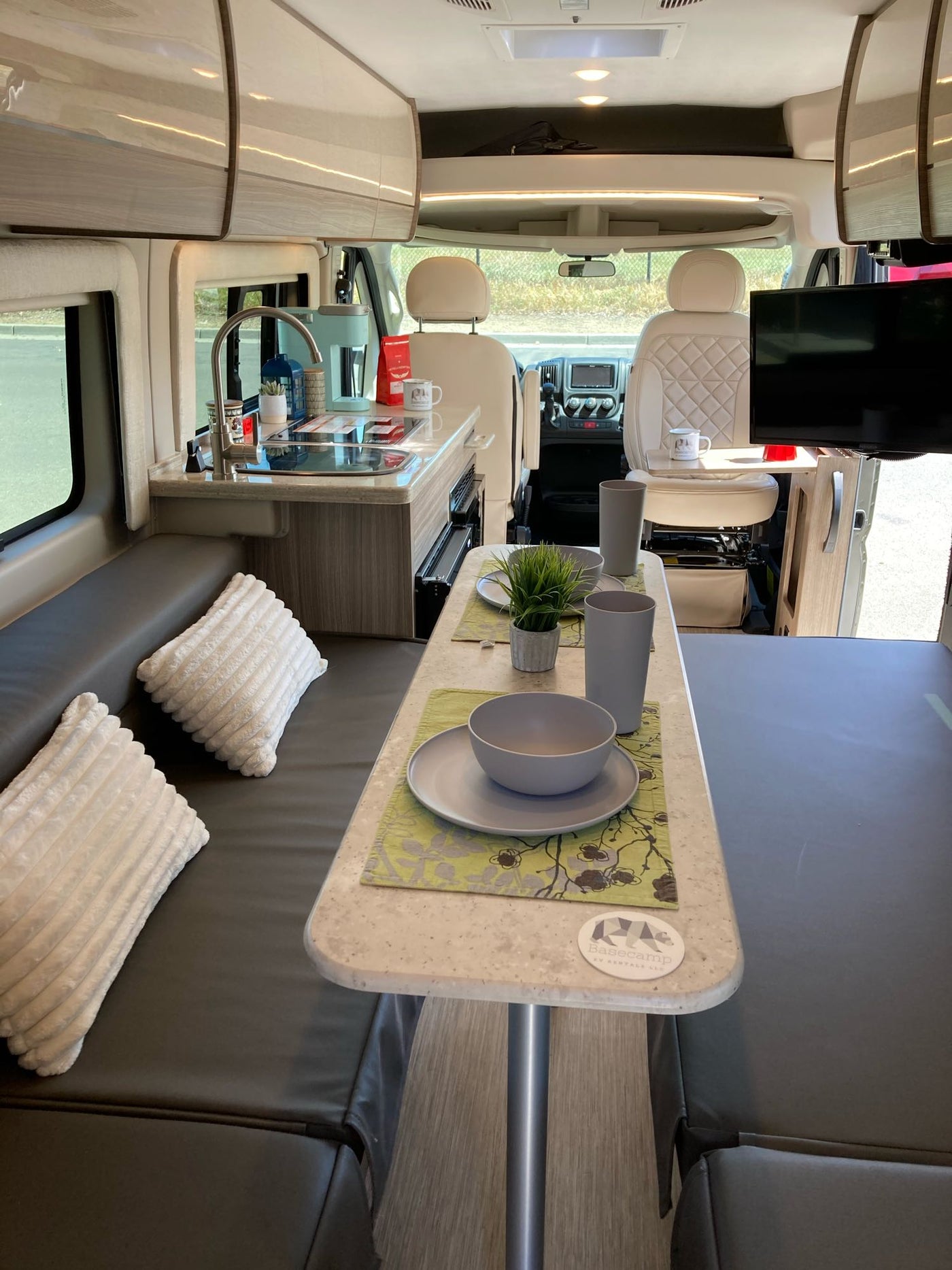 Modern RV rental interior showing a compact kitchen, dining table, and adaptable seating for comfortable journeys. — photo 13