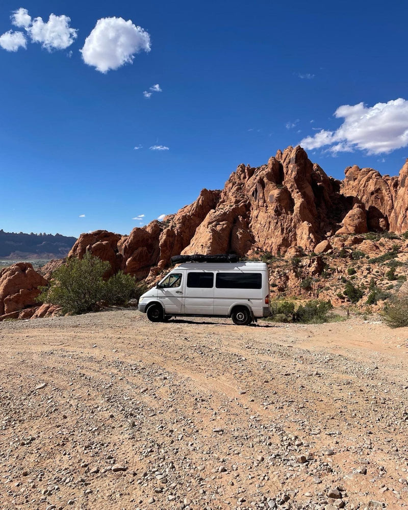 White campervan (potential RV rental) in stunning red rock desert landscape under a clear blue sky.|A white camper van — photo 1