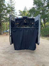 Rear view of an RV rental camper van at a campsite with its black privacy room deployed, perfect for outdoor camping convenience.