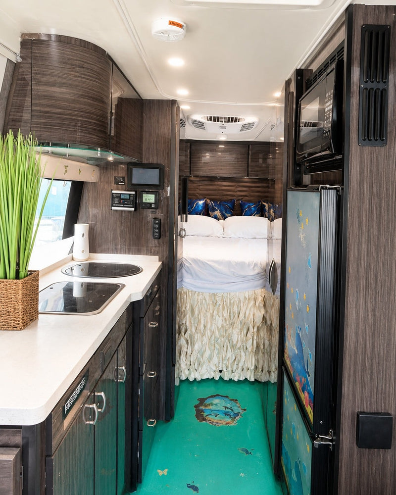  and sleek lighting for comfortable journeys.|This RV rental's cozy interior features cream seats with blue-gold marbled pillows — photo 14