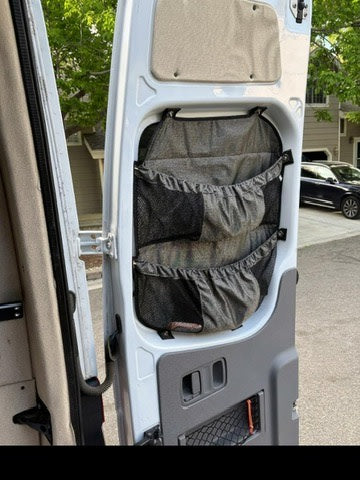 RV rental's rear door features a gray fabric organizer with mesh pockets, maximizing storage for van life essentials & camping gear.