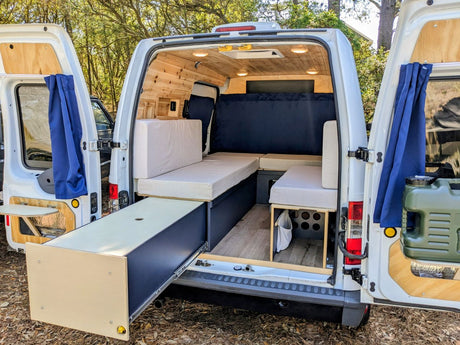 RV rental interior: Custom camper van with pull-out storage, cozy seating, and wood paneling, ready for adventure.