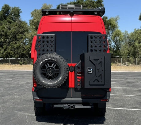 Red Storyteller Overland camper van, showing its rugged rear with a spare tire, storage, and rooftop rack—ideal for your next RV rental adventure.