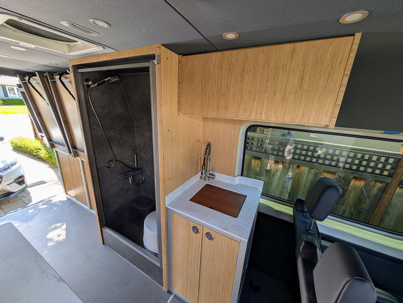 RV rental interior: A modern camper van with a sleek tiled shower, kitchenette, and bamboo storage. — photo 4