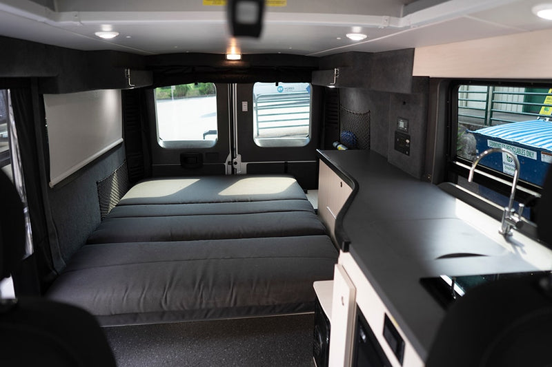 Experience a comfortable rv rental interior featuring a large bed at the rear and a well-appointed kitchen counter with a sink. — photo 3